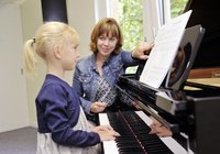 eine Jutes Kind bekommt sitzt am Klavier und bekommt Unterricht