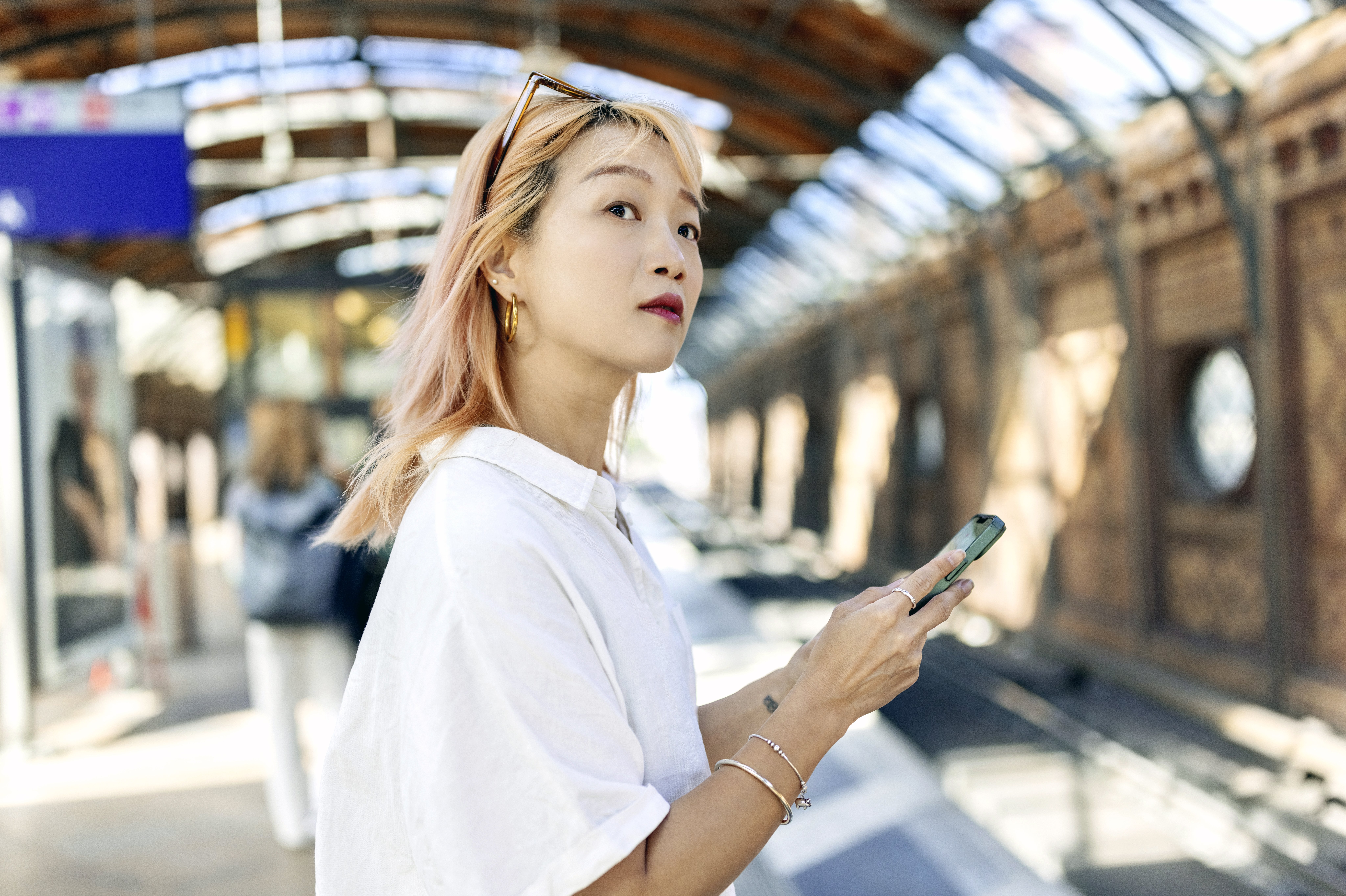 Frau mit Handy am Bahnsteig