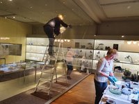 Moderne-Kuratorin Sabine Epple (auf der Leiter), Glas- und Keramikrestauratorin Ilona Faust (vorn) und Aufsichtspersonen bei der Reinigung der GRASSI-Sammlung