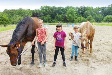 Drei Kinder mit zwei Pferden