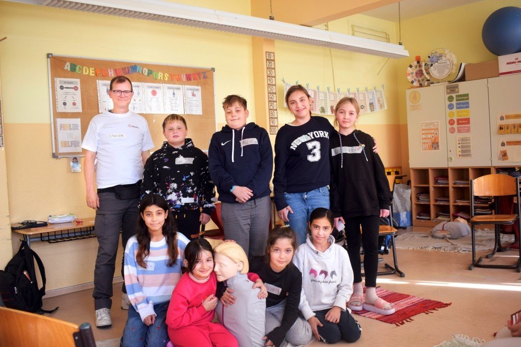 Herzretter-Trainer Sven Tausend (l.) zeigt Grundschulkindern Erste Hilfe an der Astrid Lindgren Schule