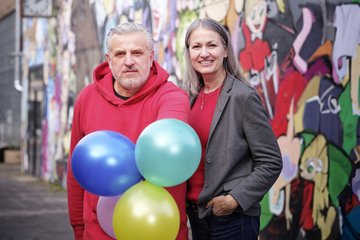 zwei Menschen mit Luftballons in der Hand 