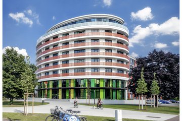 zentrale der UNITAS: ein Gebäude mit einer gewölbten Fassade, Grünfläche im Vordergrund 