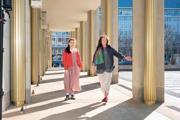 Daria (l.) trägt das ärmellose Webkleid „Juliette“ mit Webbluse „Amelie“, Sabine (r.) trägt die Webjacke „Ines“ über der Webtunika „Reflexions“