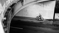 zusehen ein Mensch der mit dem Fahrrad unter einer Brücke lang fährt 