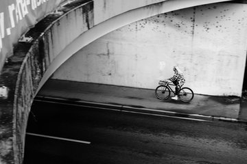 zusehen ein Mensch der mit dem Fahrrad unter einer Brücke lang fährt 