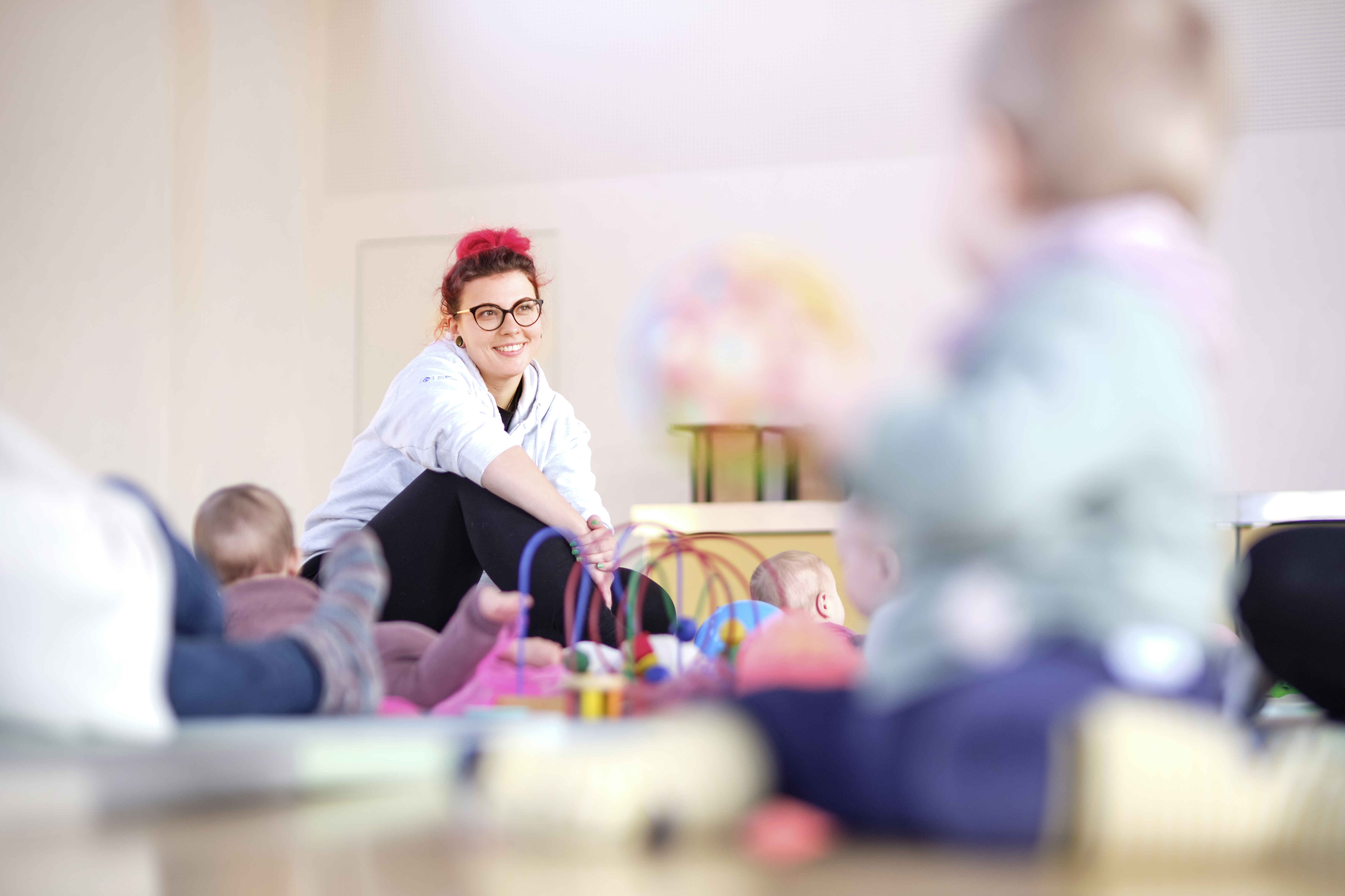 Anna die Leitern der Krabbelgruppe sind Lächeln zwischen spielenden Kindern 