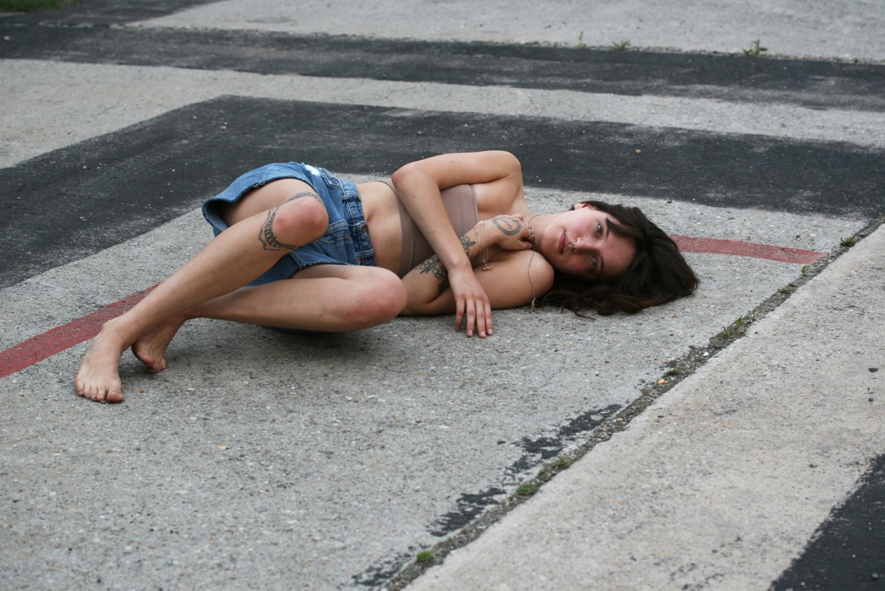Eine tätowierte Frau liegt auf Betonboden