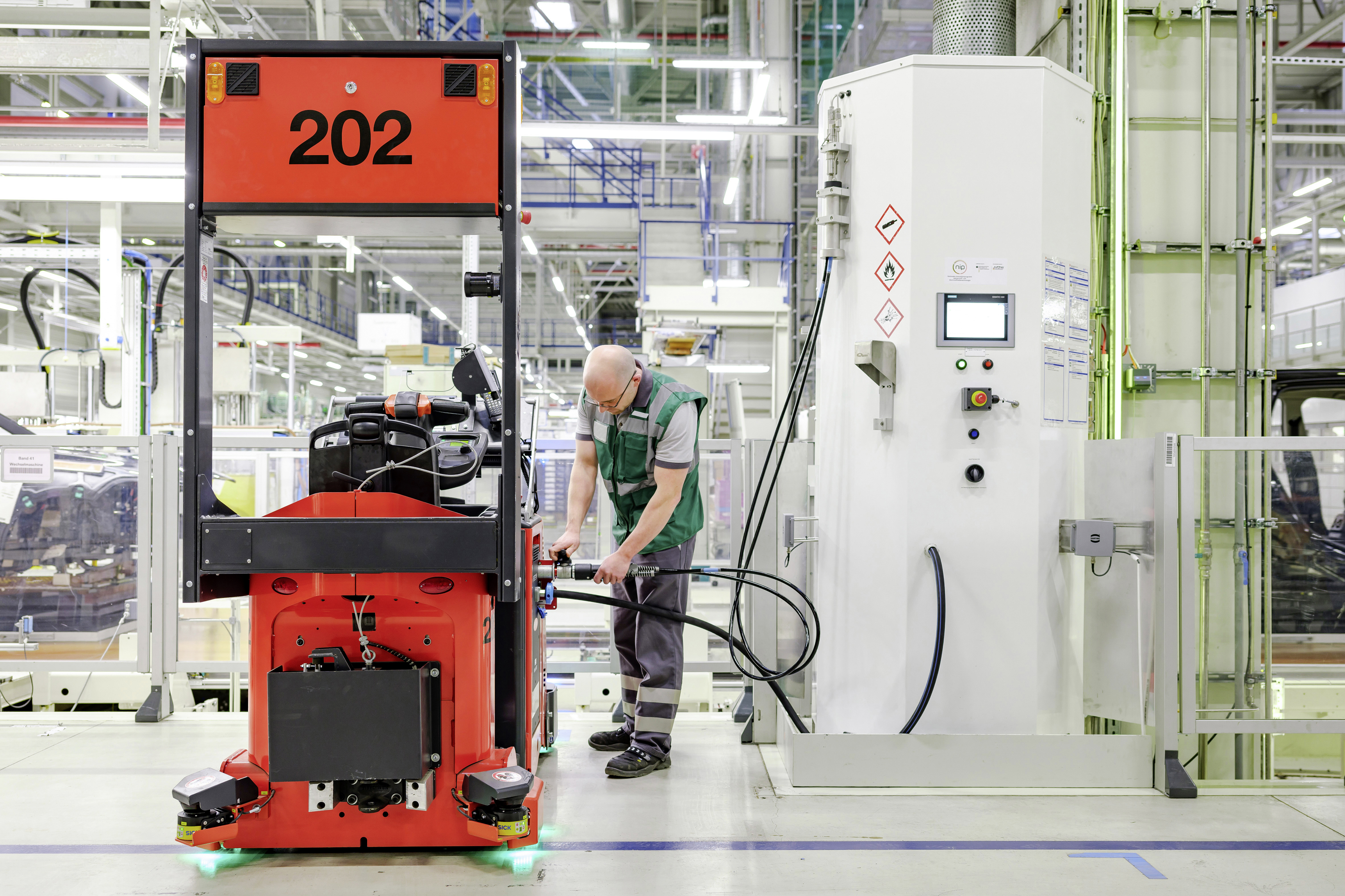 zusehen: ein Moderen Gabelstapler der Rot ist und mit Wasserstoff betankt wird 